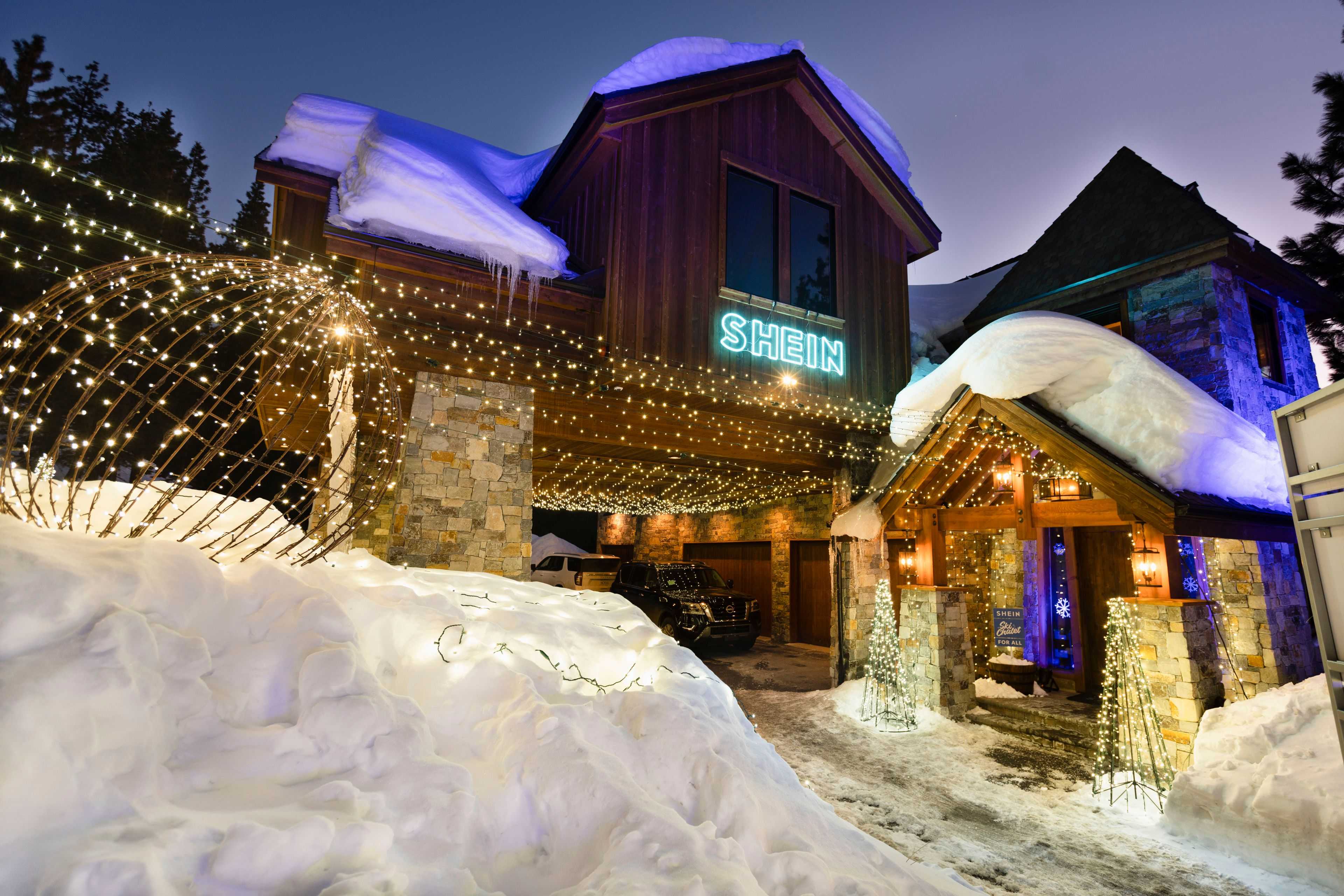 a luxury home covered in lighting and snow as the sun sets